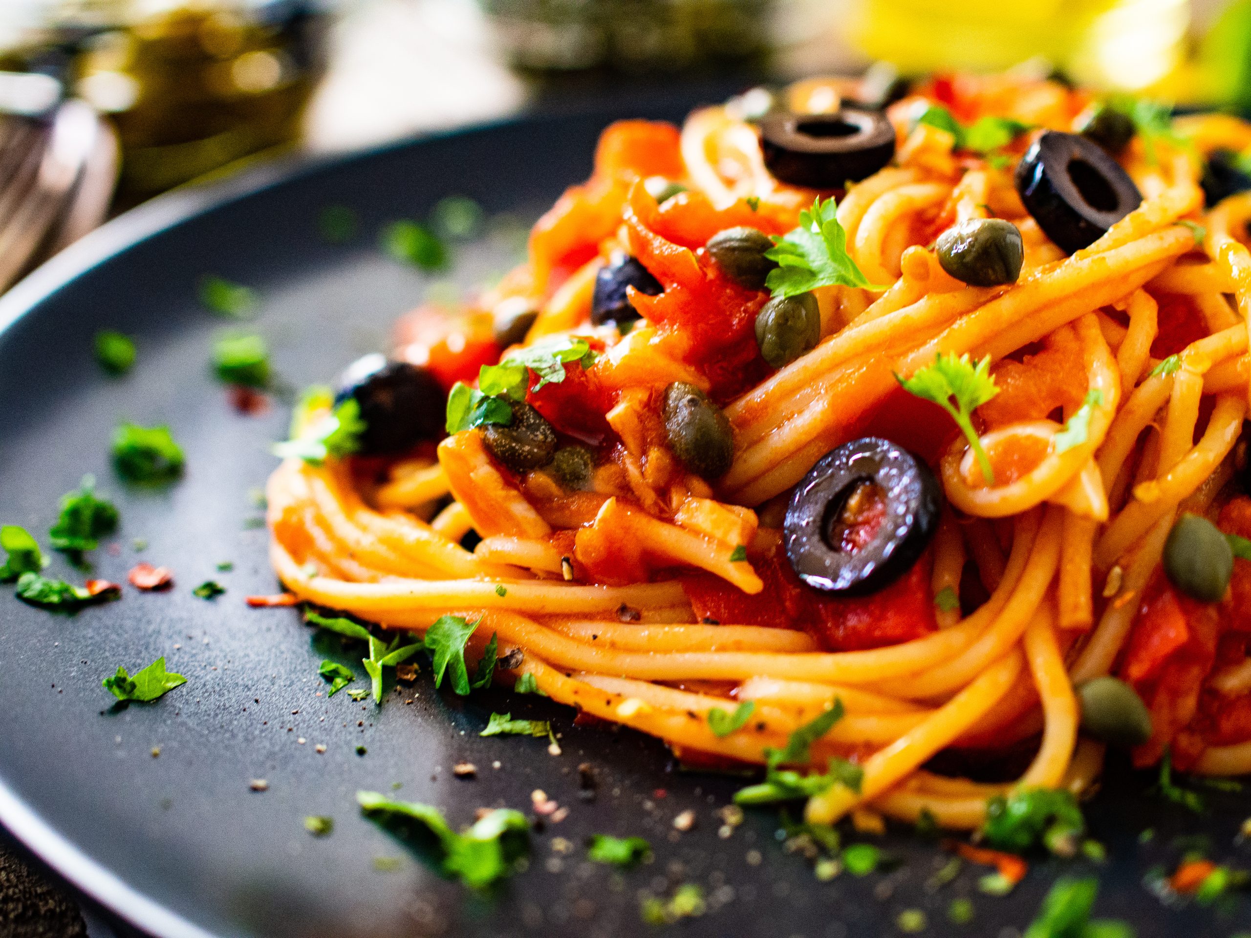 Pasta puttanesca with tomato sauce, anchovies, chilli, capers and olives on wooden table OLYMPUS DIGITAL CAMERA
